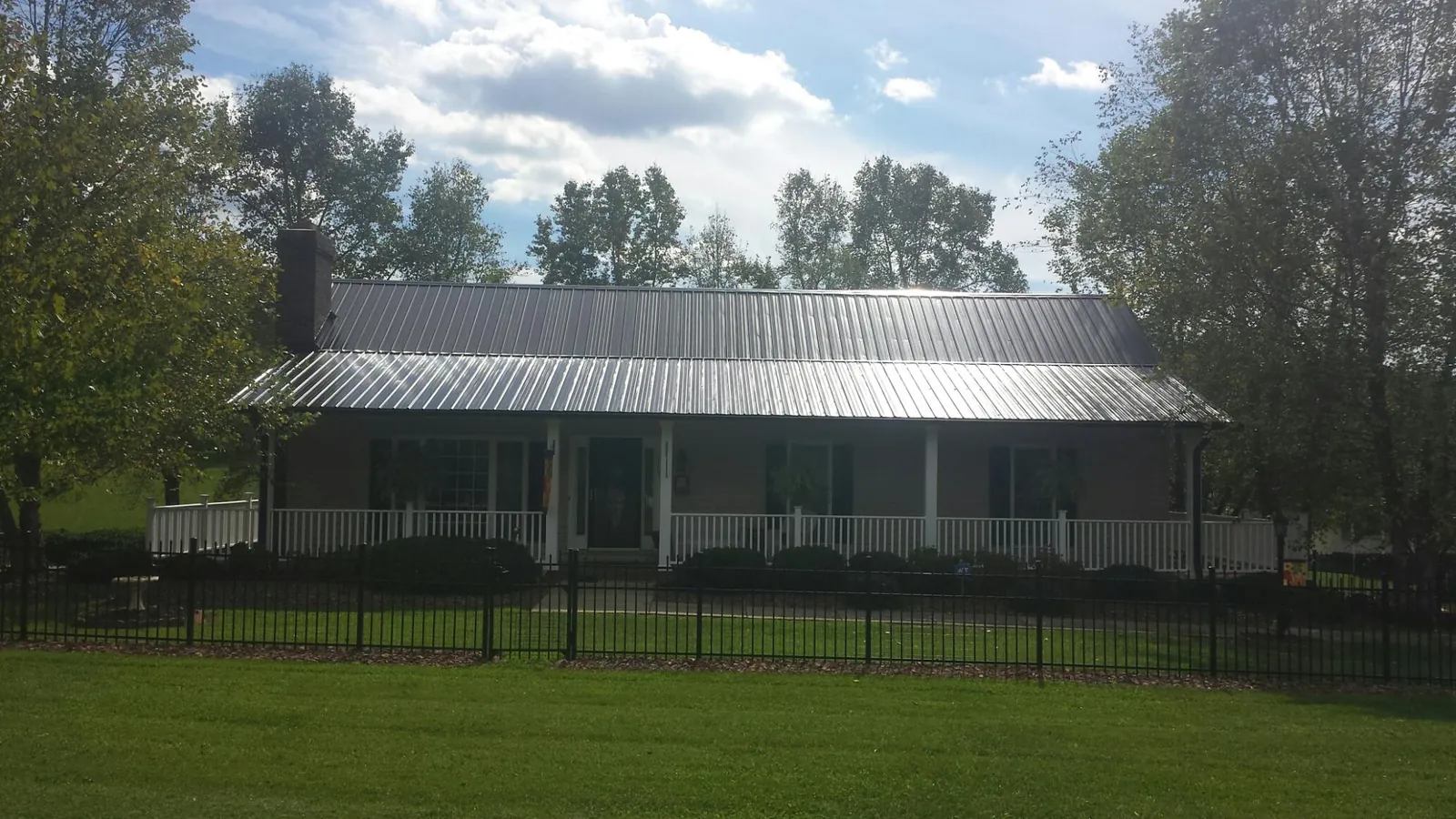 Gray metal roof on a brick ranch with a full width front porch — Gutter Guard Installation work by our crew in Lynnfield