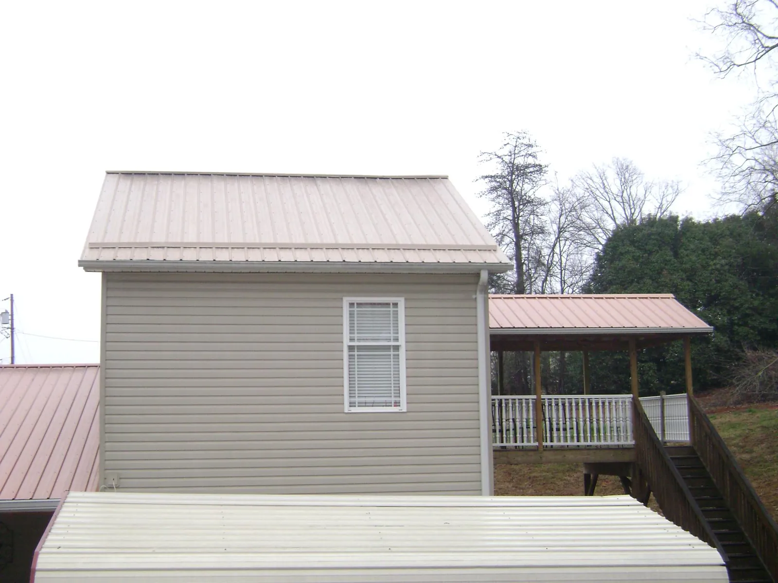 Tan metal roofs on a two story addition and attached porch, from a Roof Replacement job in Lynnfield