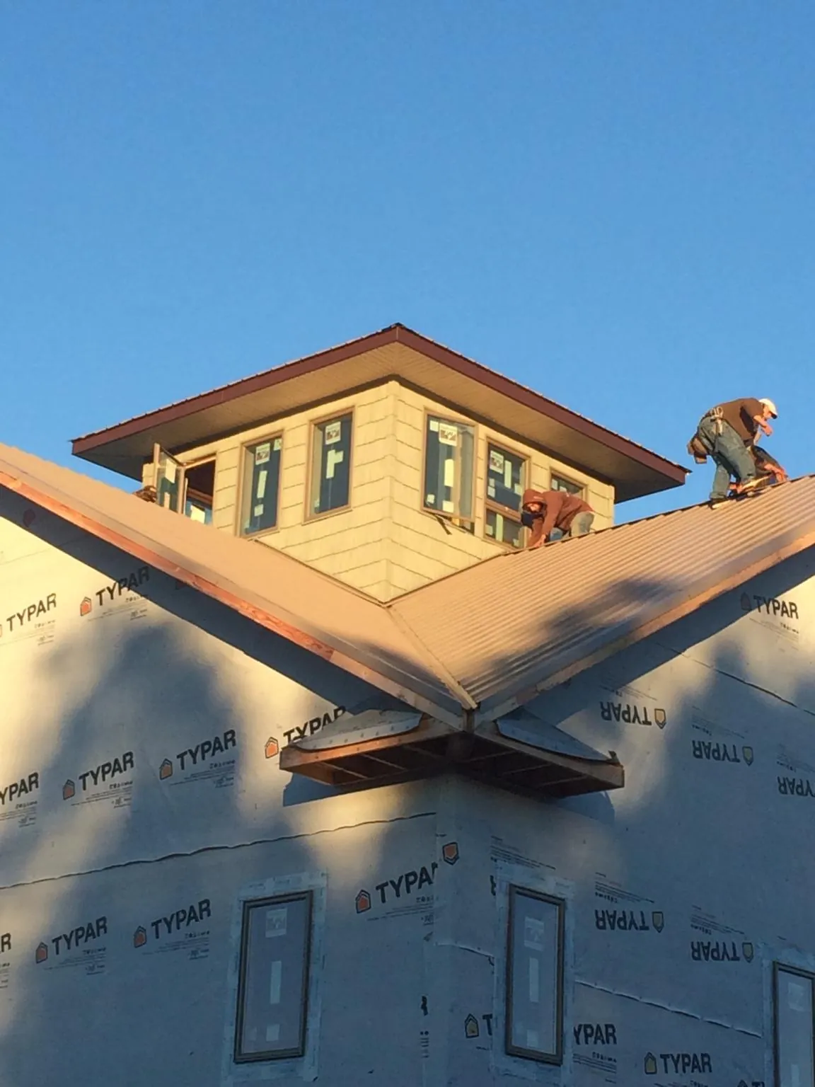 Roofers working around a rooftop cupola on a new metal roof at sunset — Roof Waterproofing in Lynnfield by Roofing Brothers